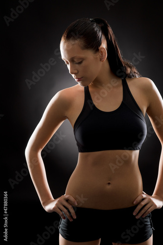 Young fit woman sport posing on black © CandyBox Images
