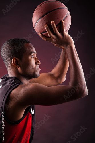 Portrait of a young male basketball player against black backgr