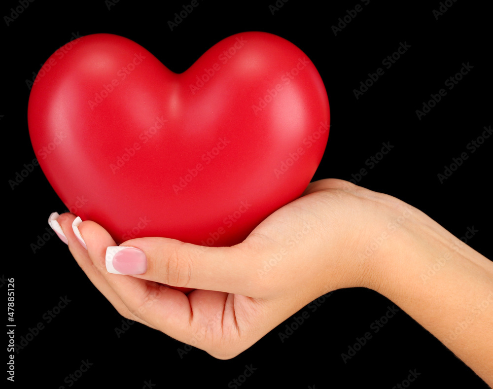 Red heart in woman's hand, on black background close-up Red heart in woman's hand, on black background close-up
