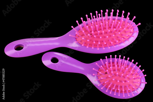 two purple hair brushes on black background