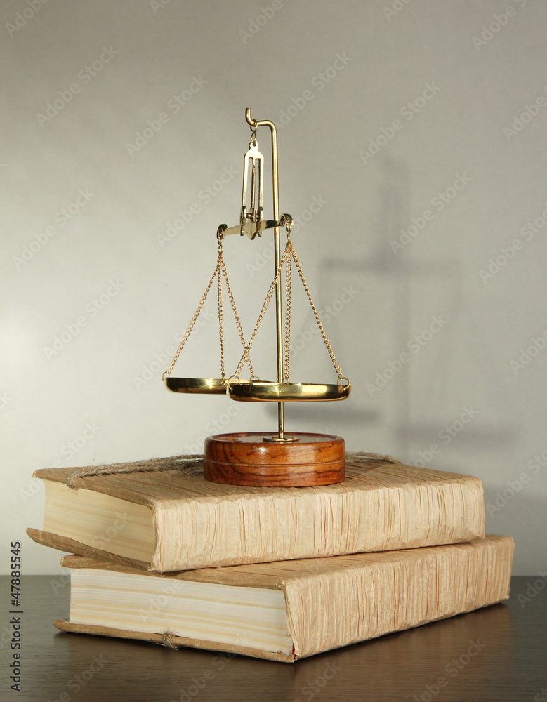 Gold scales of justice and books on grey background Gold scales of justice and books on grey background