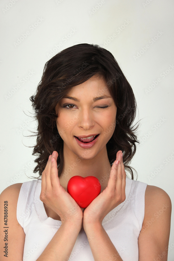 Girl winking holding heart in hands Girl winking holding heart in hands