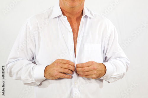 man buttoning his white office shirt in the morning