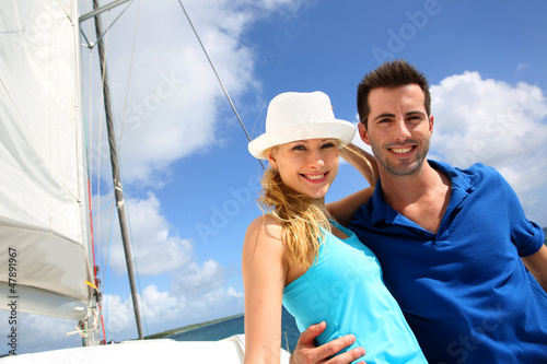 Smiling rich young couple on a sailboat in Caribbean sea