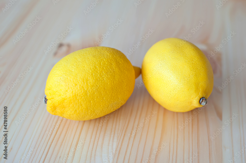 Two yellow Lemon lie on a wooden table