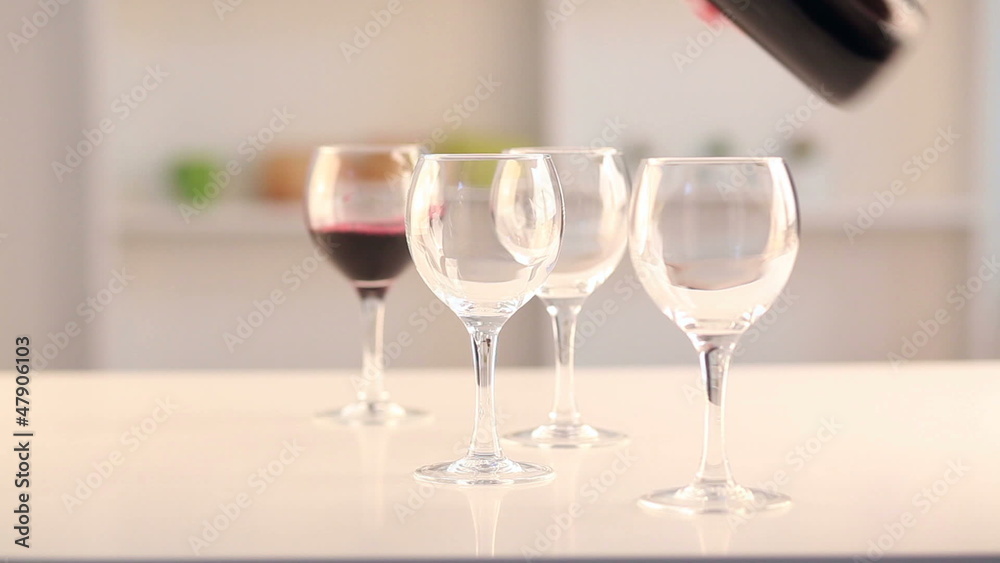 Pouring red wine in four glasses Pouring red wine in four glasses