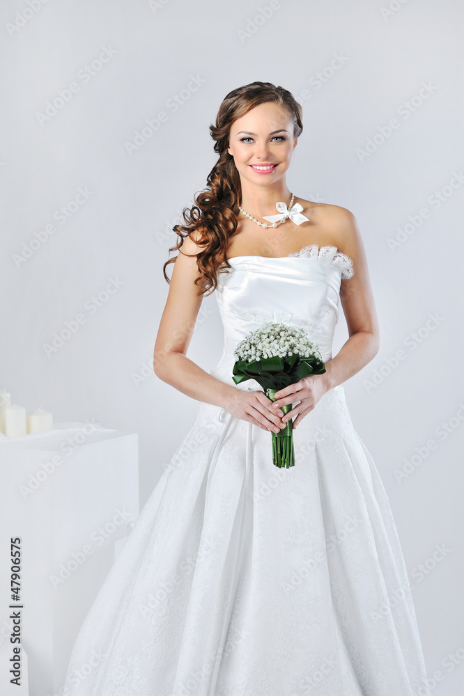 Beautiful smiling girl in a white wedding dress on a white backg Beautiful smiling girl in a white wedding dress on a white backg