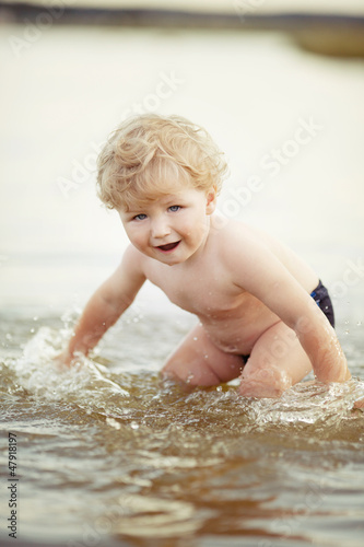 Fototapeta Naklejka Na Ścianę i Meble -  little funny boy playing in lake