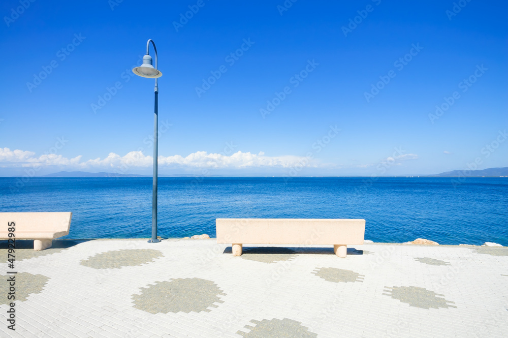 Bench and lamp on the sea in Argentario, Tuscany, Italy.