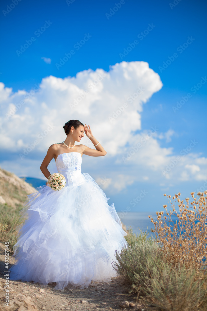 wedding: Happy bride on cliff on background blue sea in summer