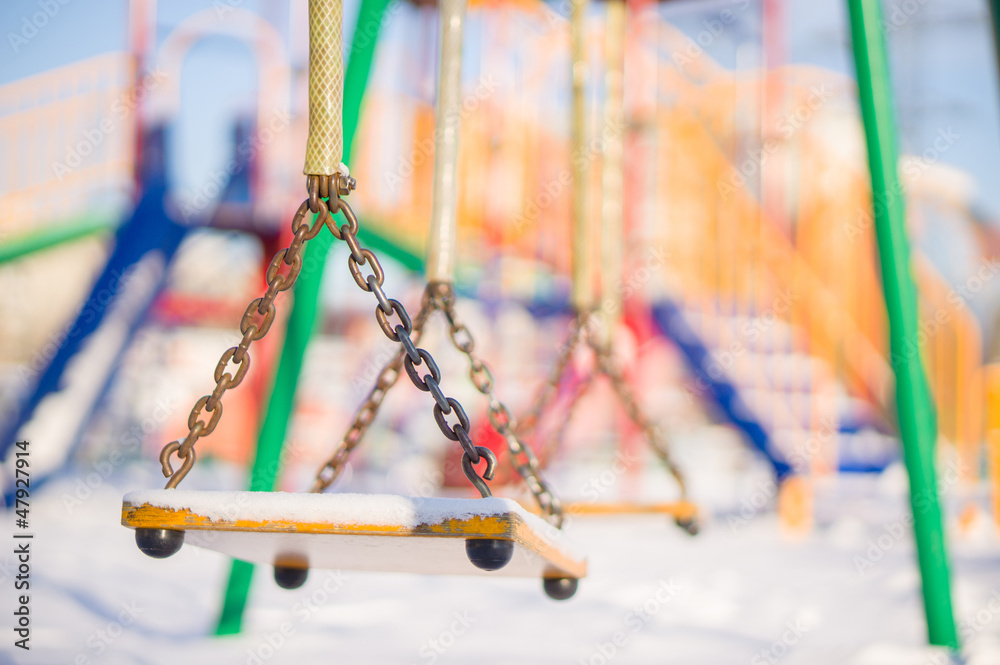 Kids chain swings on winter playground covered with snow