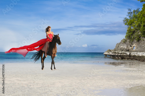 young beautiful woman riding a horse on tropical beach