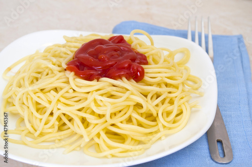 Spaghetti with ketchup in a bowl with a fork.