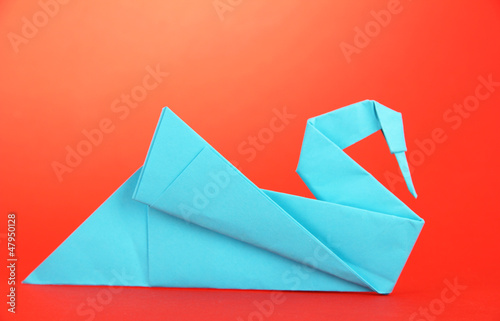 Origami swan on red background.