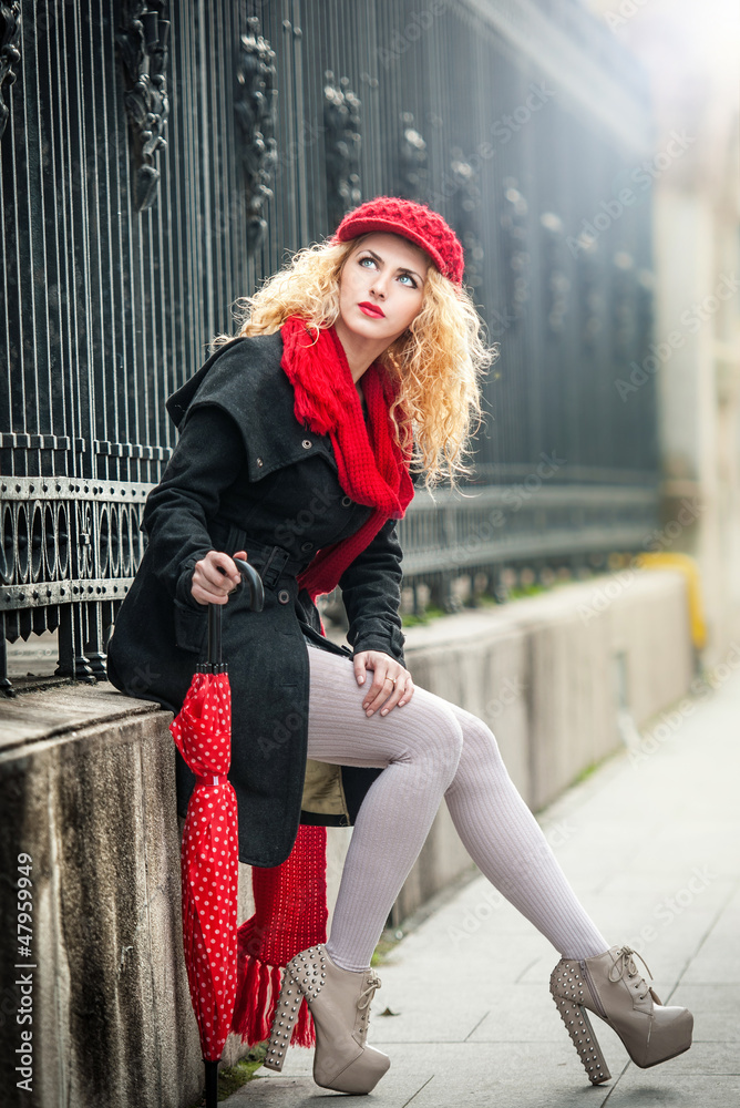 Beautiful fashionable young girl with red umbrella in the street