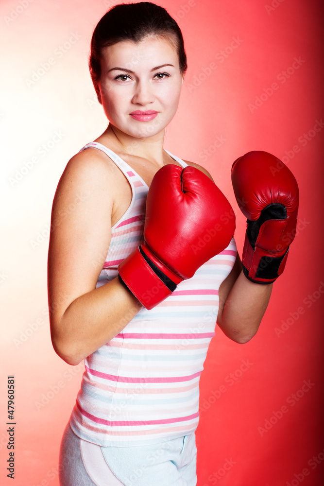 Attractive young woman wearing red boxing gloves