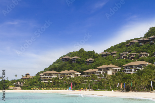 tropical sea, beach and hotel on blue sky background