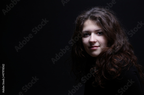 Portrait of a curly-haired girl on black