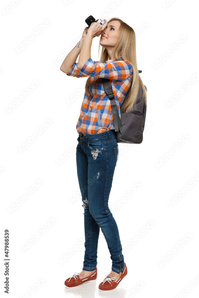 Full length of young female with backpack shooting with camera