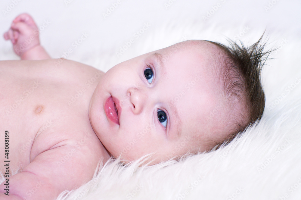 The happy three-months baby lies on a fur plaid The happy three-months baby lies on a fur plaid