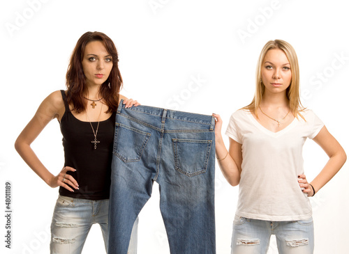 Two sexy friends posing with a pair of jeans