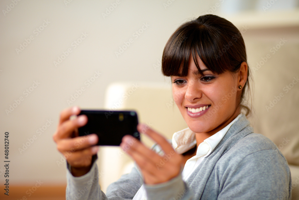 Smiling young woman reading a message on cellphone Smiling young woman reading a message on cellphone