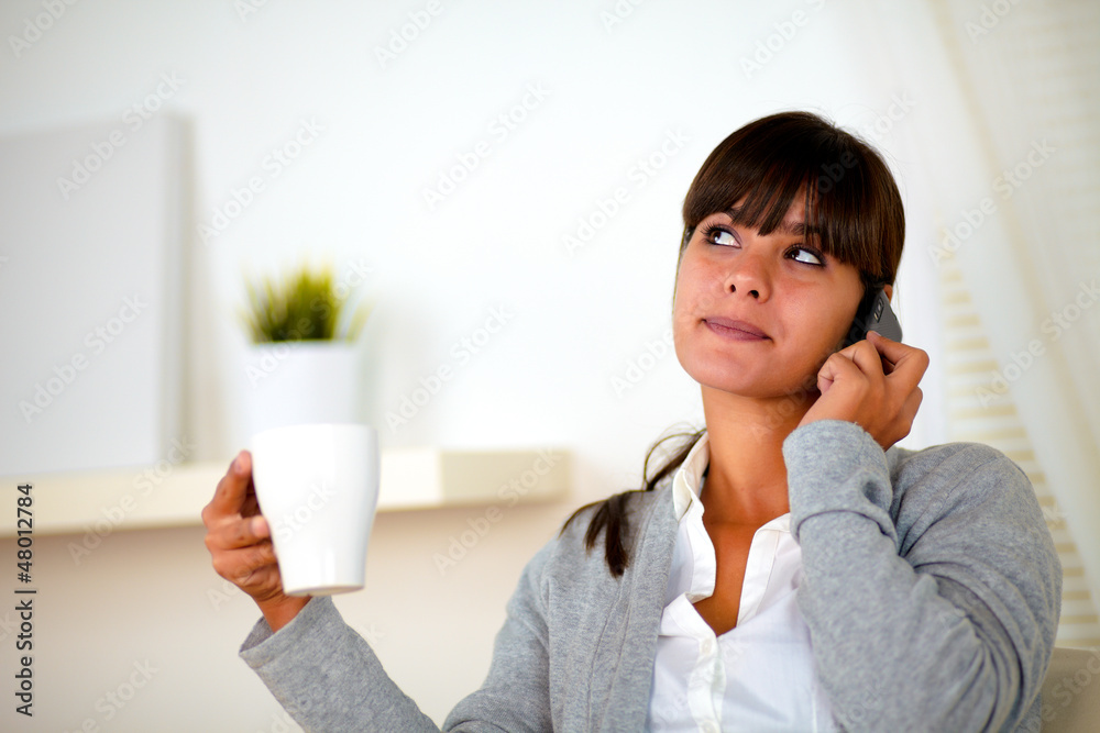 Adult woman with a white mug speaking on cellphone Adult woman with a white mug speaking on cellphone