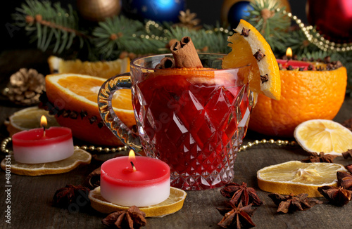 Fragrant mulled wine in glass with spices and oranges around