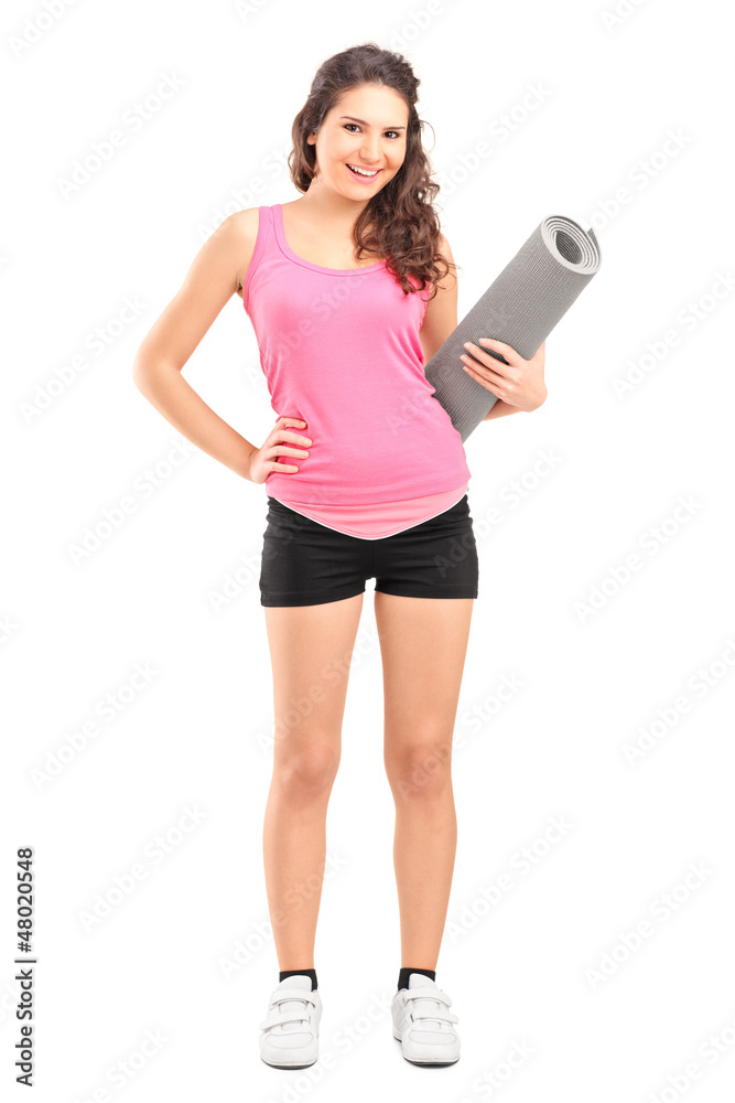 Full length portrait of a female athlete holding a mat Full length portrait of a female athlete holding a mat