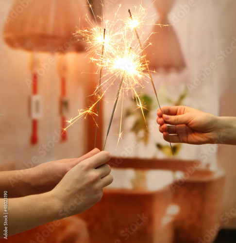 beautiful sparklers in woman hands on room background.
