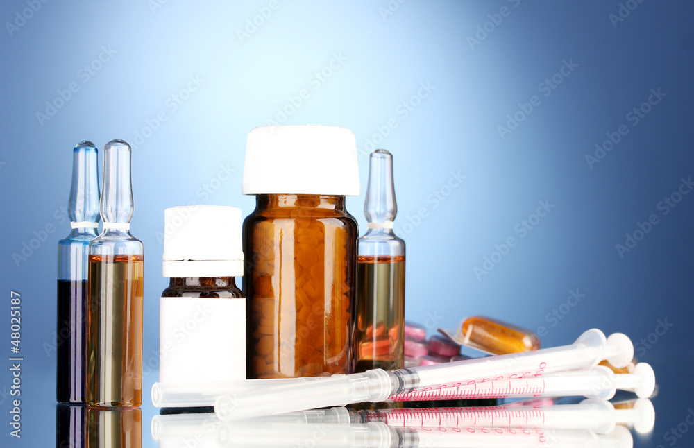medical ampules, bottles, pills and syringes on blue background medical ampules, bottles, pills and syringes on blue background