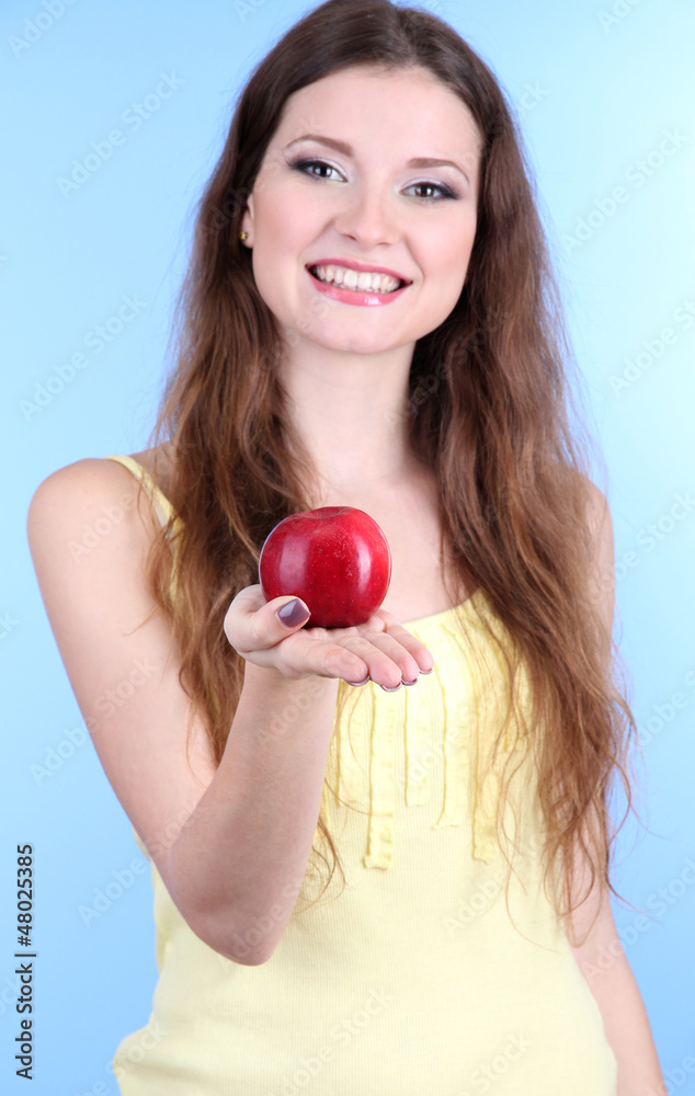 Beautiful woman with apple on blue background Beautiful woman with apple on blue background