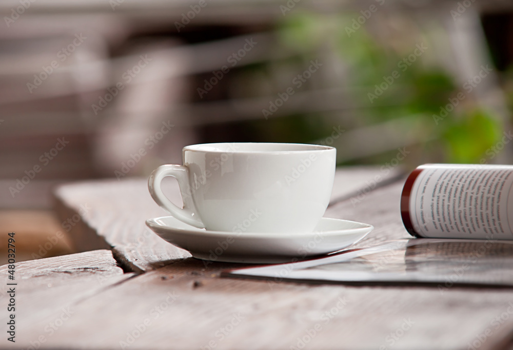 Fototapeta premium White cup with magazine on the wood table