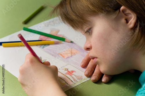 Close up of a girl with down syndrome drawing.