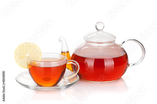 Glass teapot and cup of black tea with lemon slice