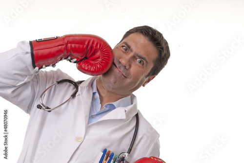 Portrait of young doctor hitting himself with boxing gloves.