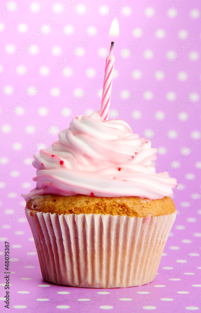 tasty birthday cupcake with candle, on violet background tasty birthday cupcake with candle, on violet background