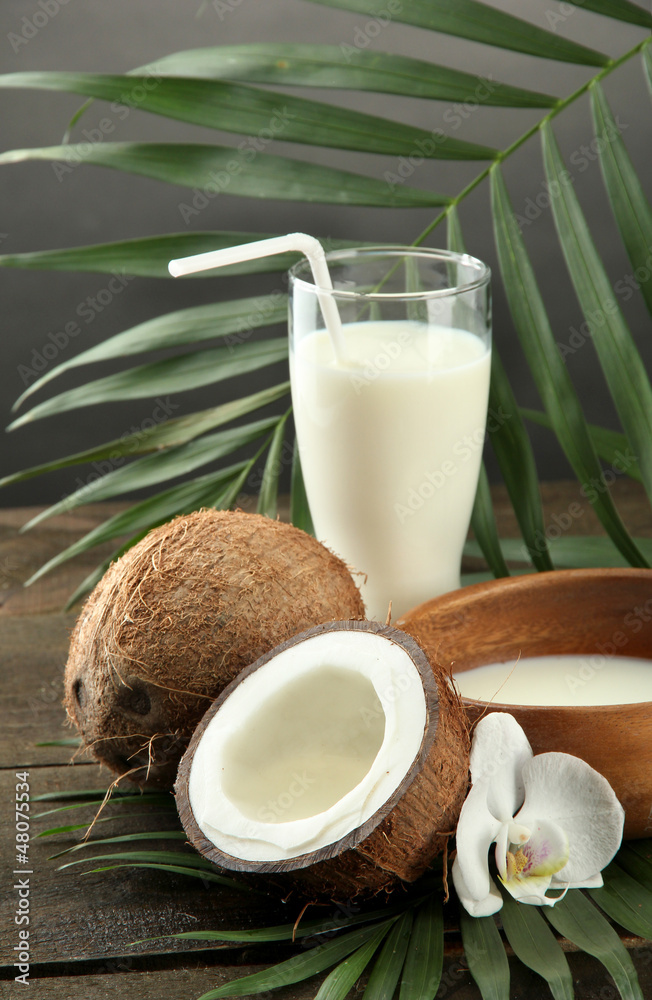 Coconut with glass of milk, on wooden table, on grey Coconut with glass of milk, on wooden table, on grey