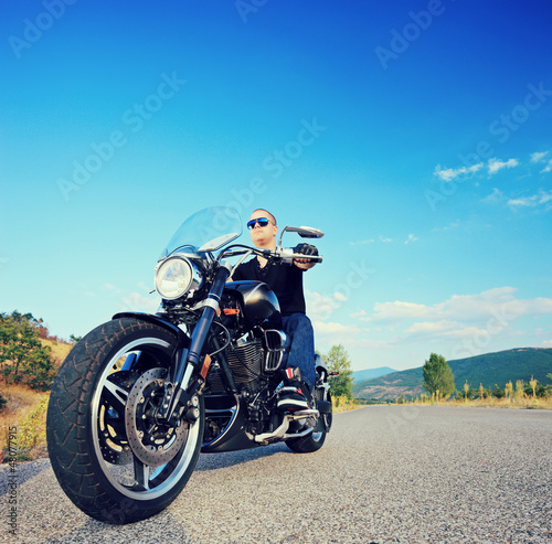 Fototapeta Naklejka Na Ścianę i Meble -  Biker riding a customized motorcycle on an open road