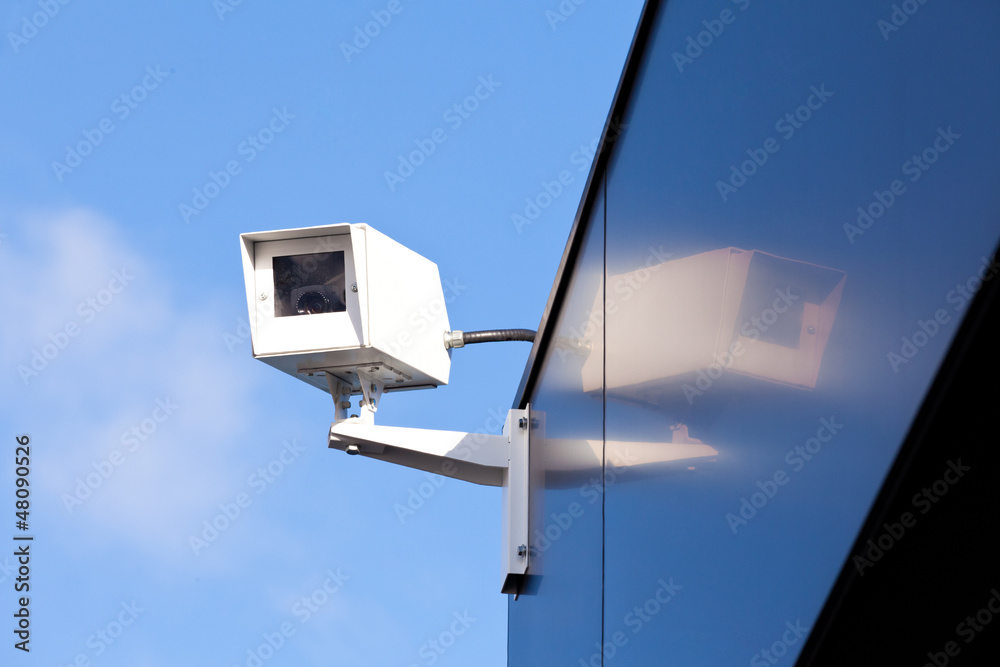 Security camera reflected on shiny building facade Security camera reflected on shiny building facade