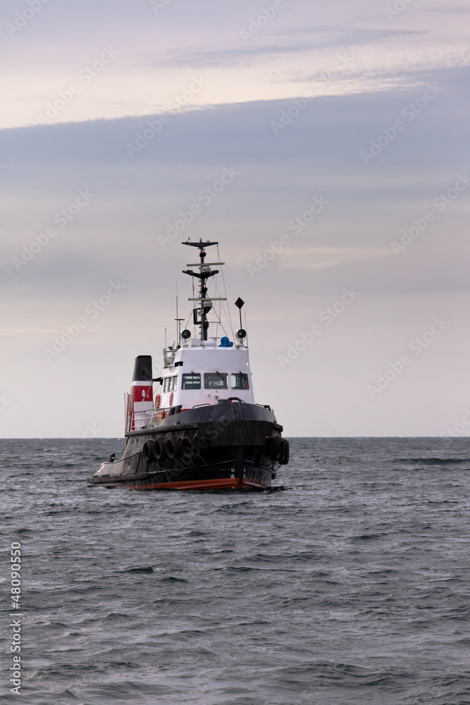 Tugboat floating in wait on calm ocean at anchor