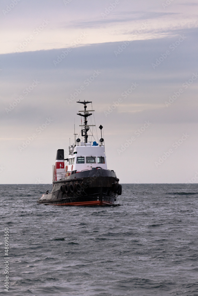 Tugboat floating in wait on calm ocean at anchor Tugboat floating in wait on calm ocean at anchor