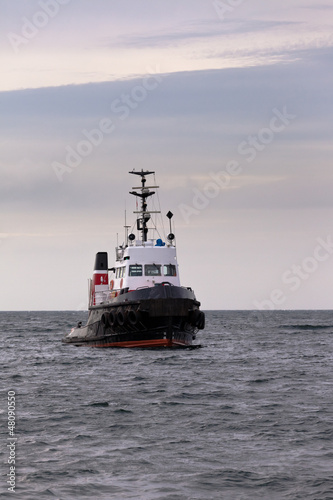 Tugboat floating in wait on calm ocean at anchor