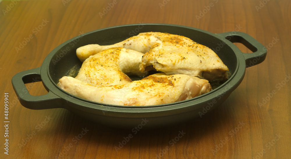 Fried appetizing chicken legs on black pan side view