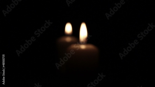 Two romantic  burning candles in dark .  Blurred scene