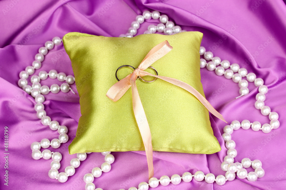 Wedding rings on satin pillow on purple cloth background Wedding rings on satin pillow on purple cloth background