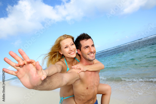 Man giving piggyback ride to girlfriend at the beach © goodluz