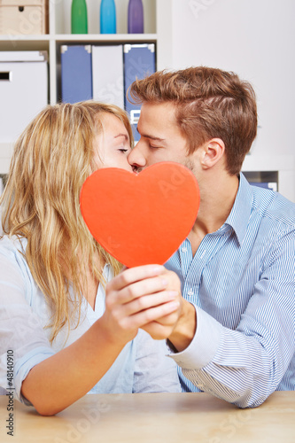 Paar küsst sich hinter rotem Herz