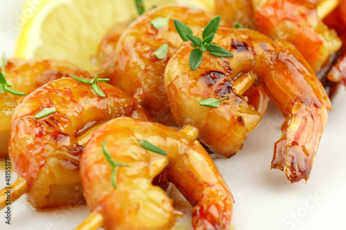 Glazed shrimp skewers with thyme and lemon closeup