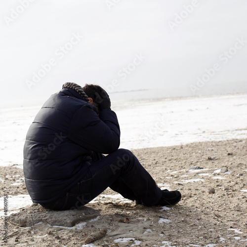 Lonely man sitting on sand